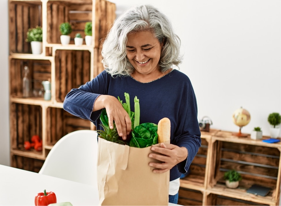 Midlife woman in kitchen unpacking groceries